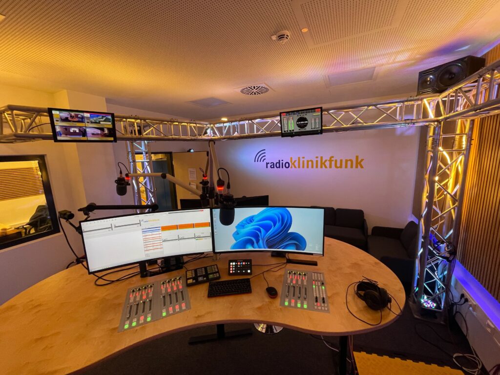 A desk with multiple monitors and a microphone.